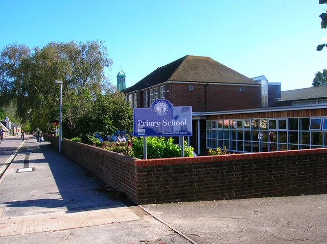 The Priory School sign and buildings in Lewes, with the clock tower behind.